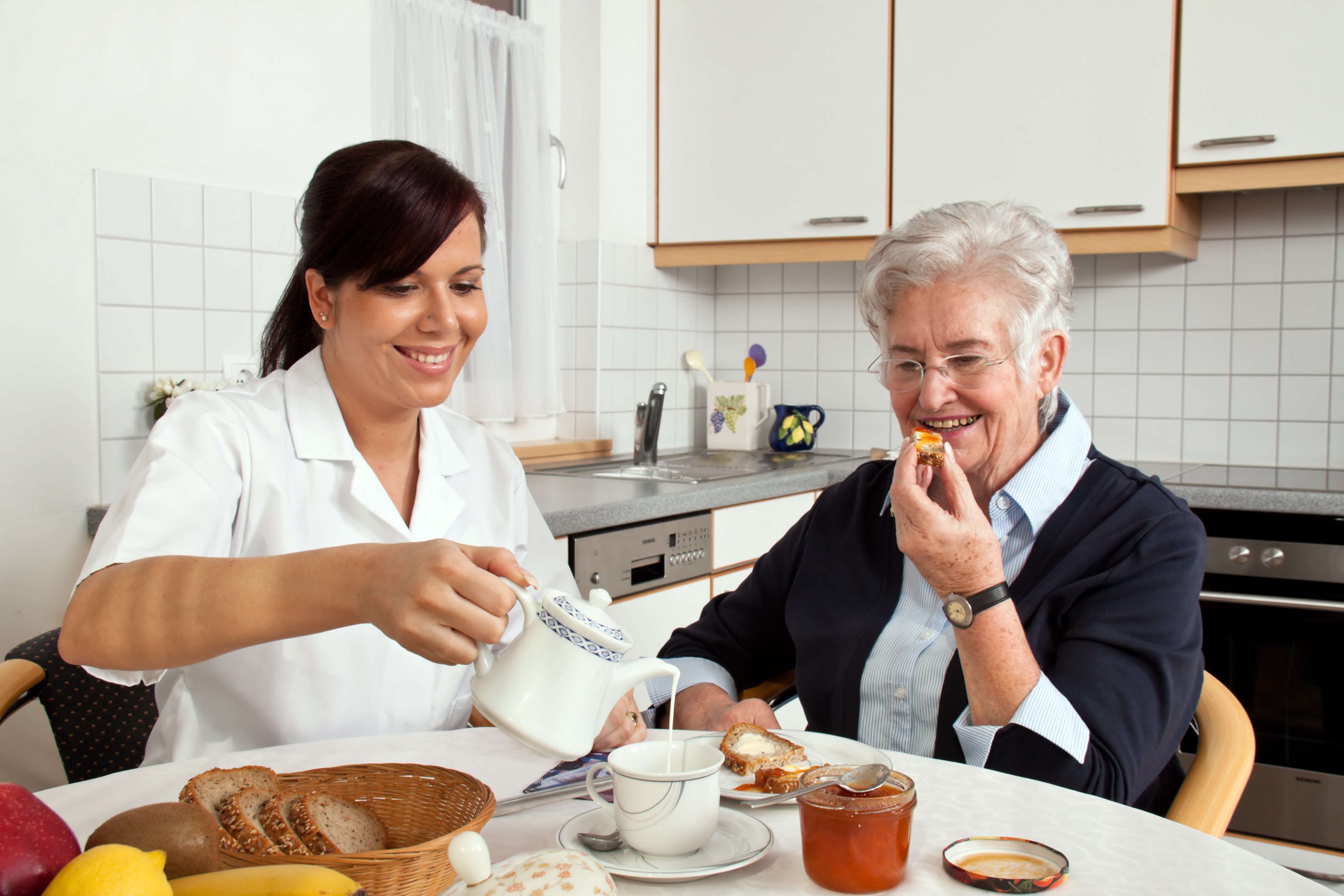 A live-in caregiver helping an elderly man with daily activities in a cozy home setting.