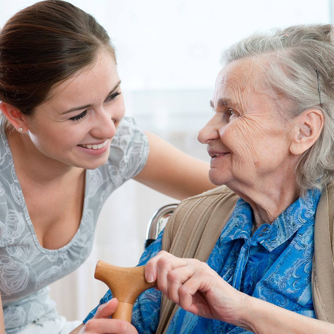 a caregiver sitting with a smiling elderly woman