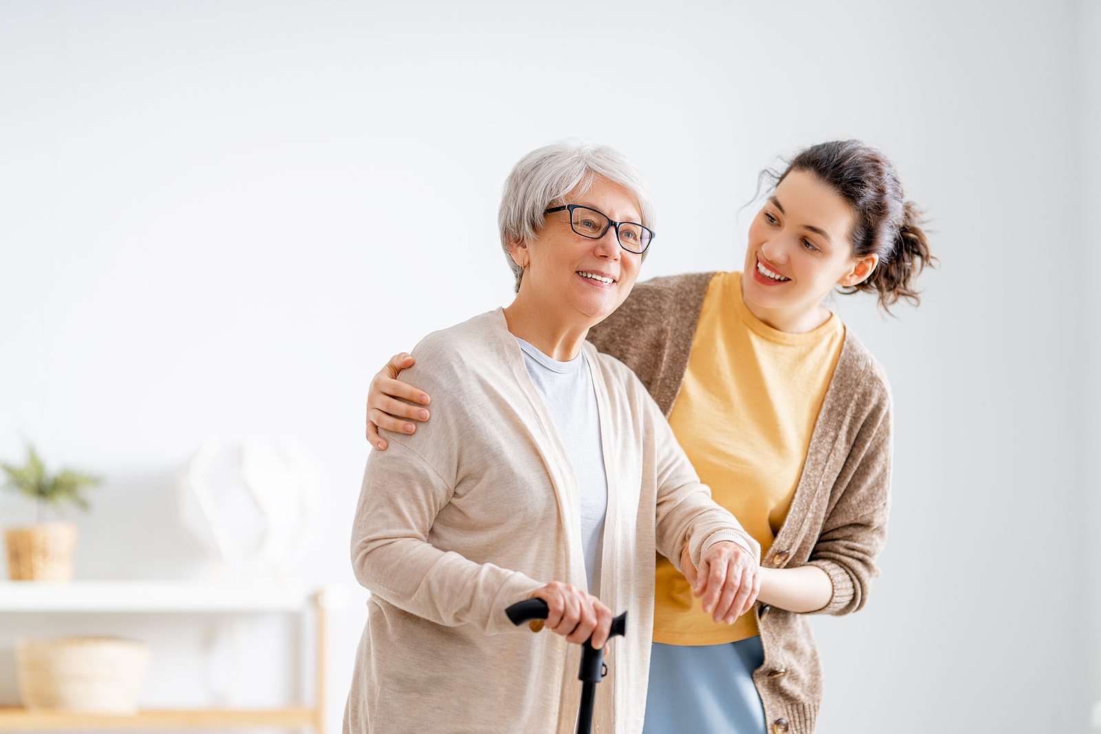 a friendly caregiver helping an elderly woman navigate her home safely