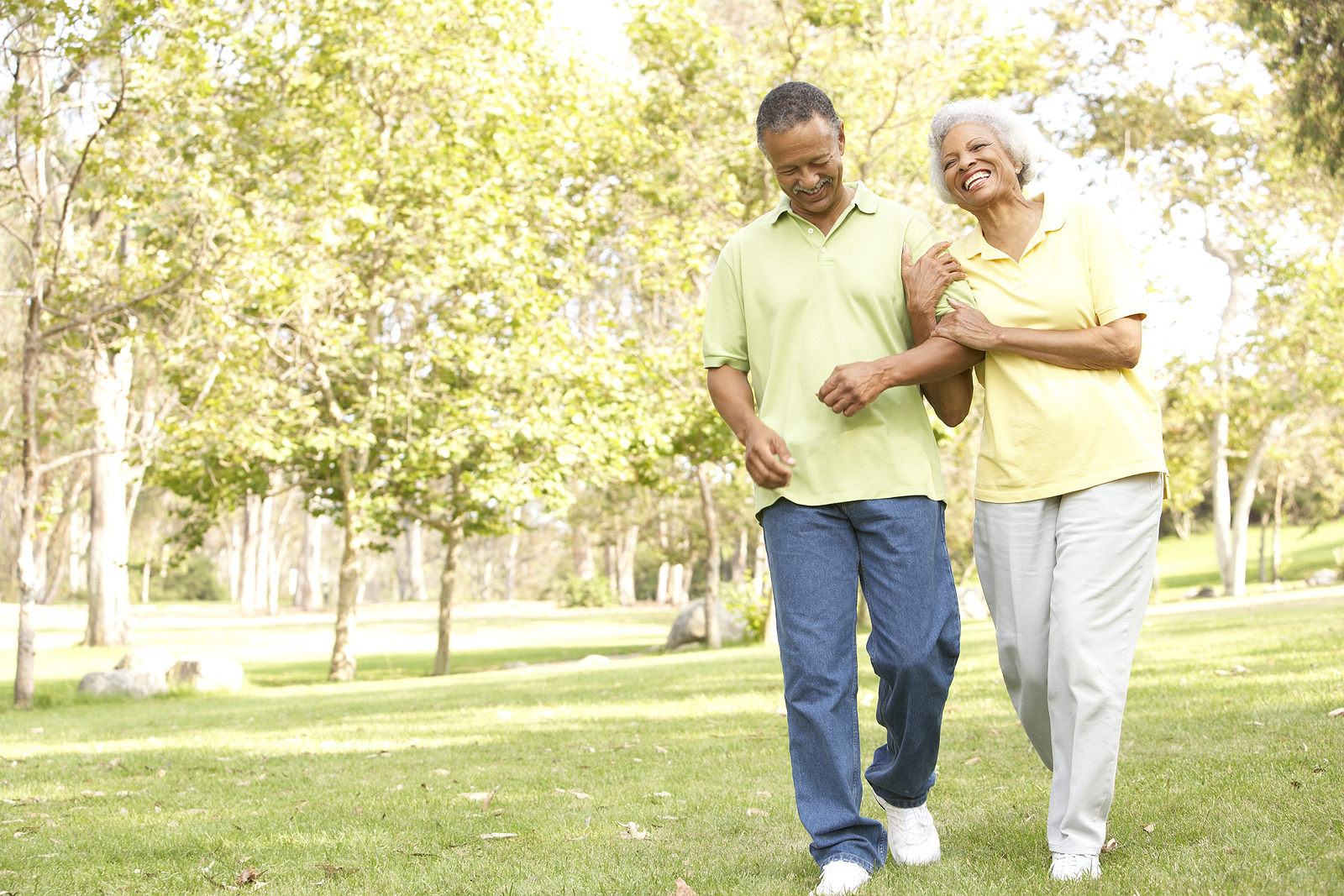 A smiling senior couple walks in the park, happy to be enjoying some fun senior activities.