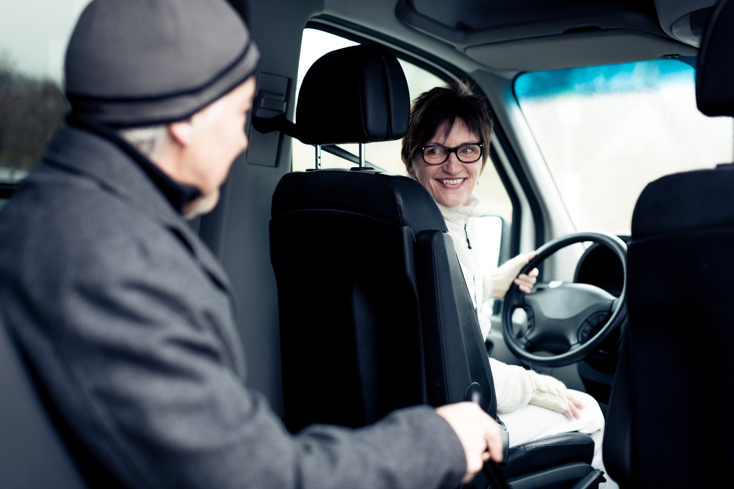 A female driver helps an older man by providing transportation services for seniors.
