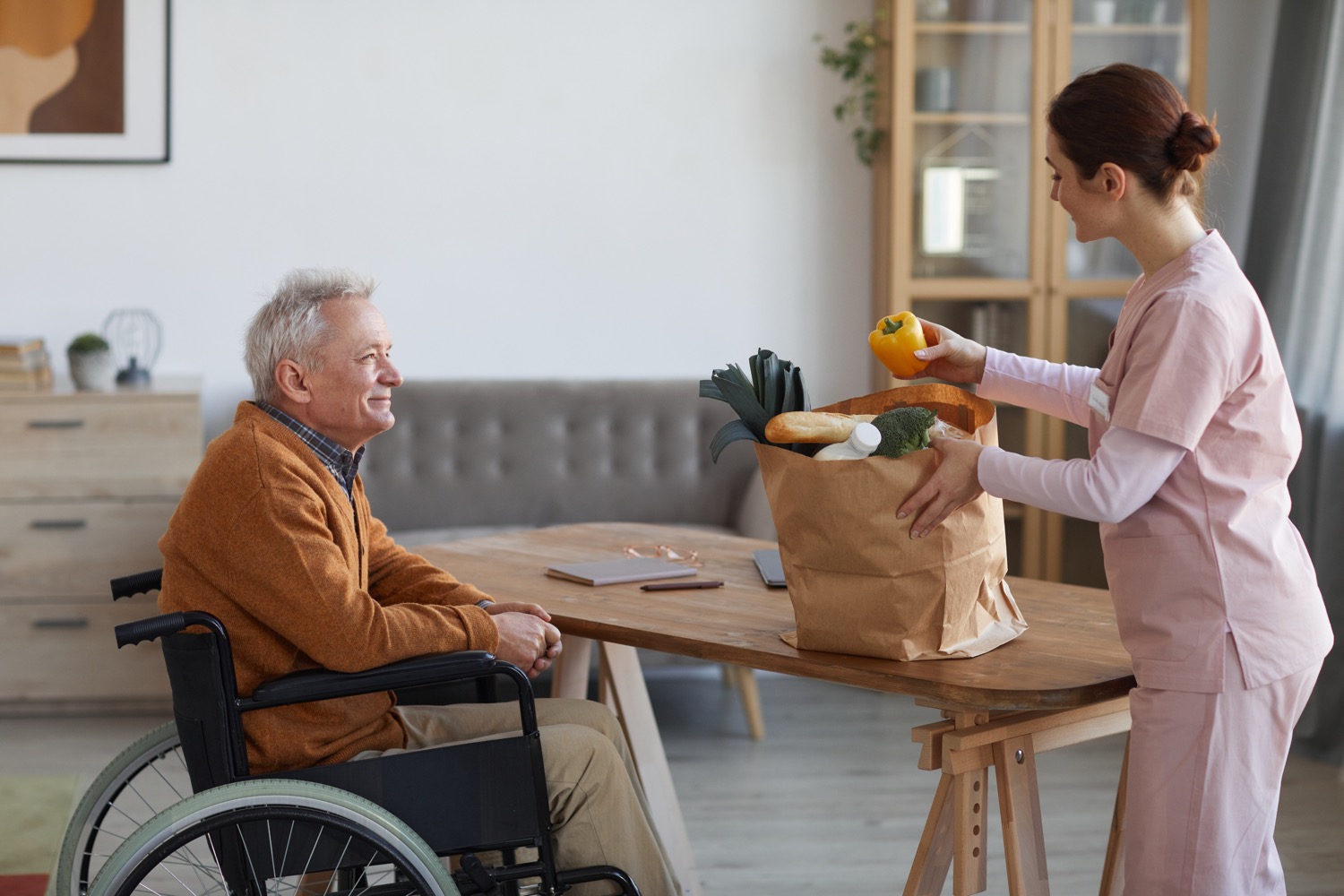 A caregiver brings an older man groceries to ensure food safety for older adults.