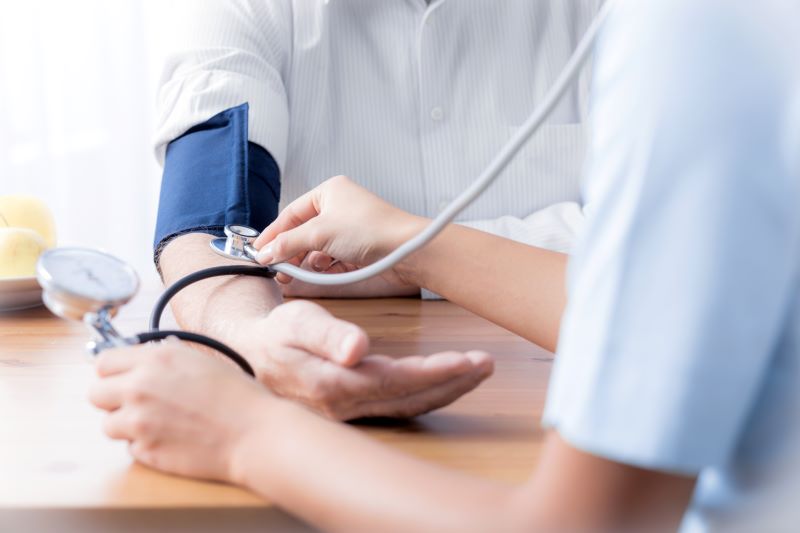 A live-in caregiver checks the blood pressure of her senior client.